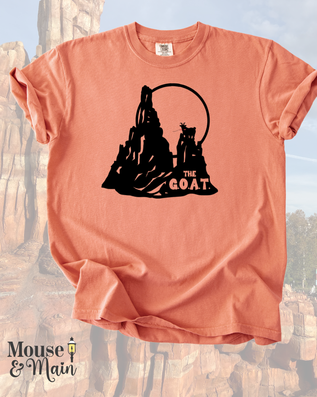 Vintage-style graphic tee inspired by a classic Disney thrill ride, showing a goat and mountain silhouette with looping track details and 'THE G.O.A.T.' text."