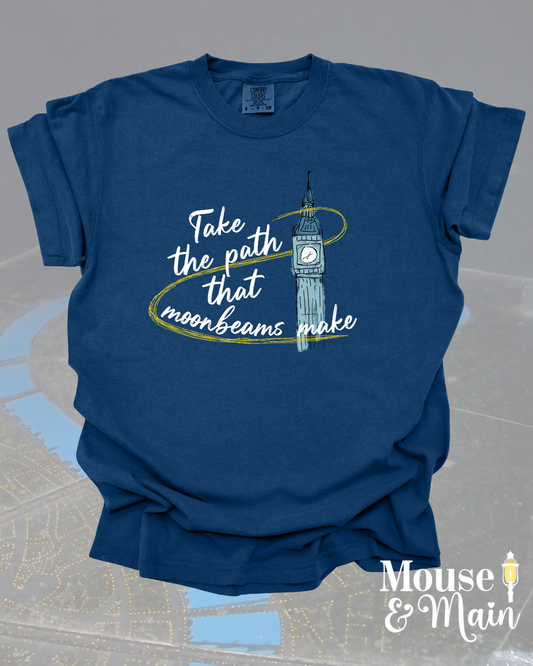 Navy blue Comfort Colors t-shirt with the quote 'Take the path that moonbeams make' and a hand-drawn clock tower wrapped in a golden swirl, inspired by Peter Pan’s Flight.